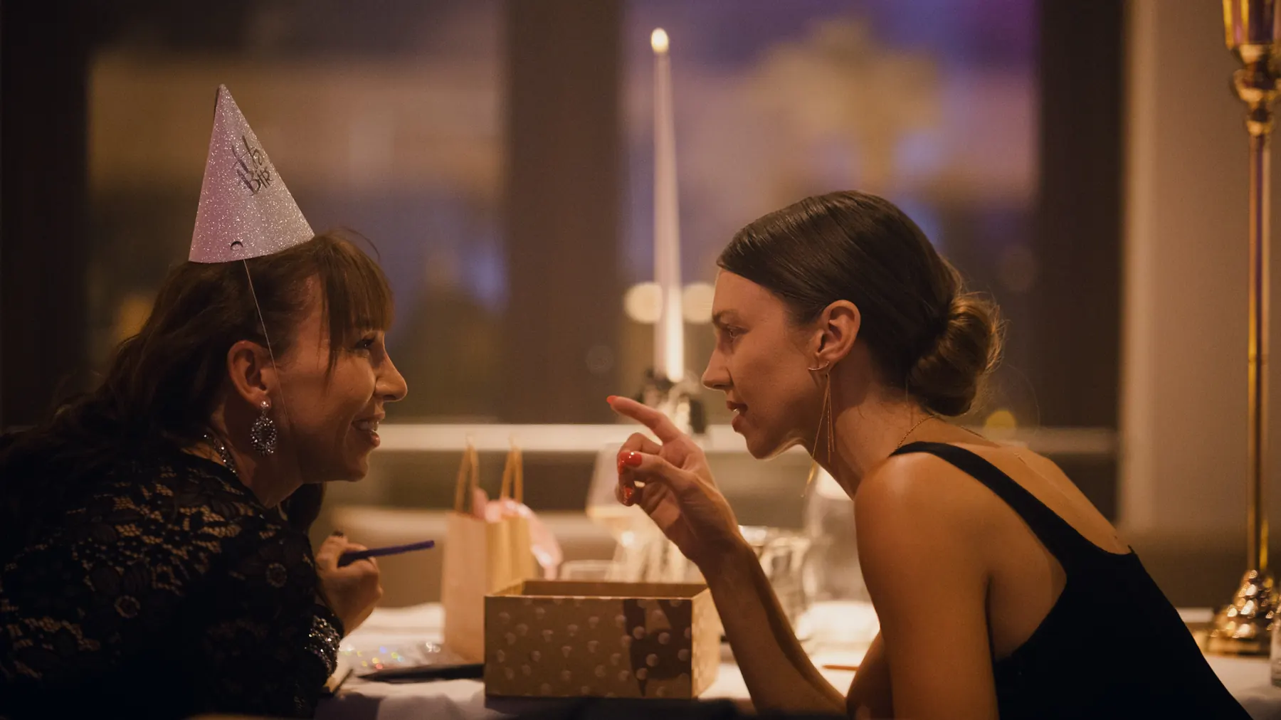 Two women sharing a candlelit birthday moment