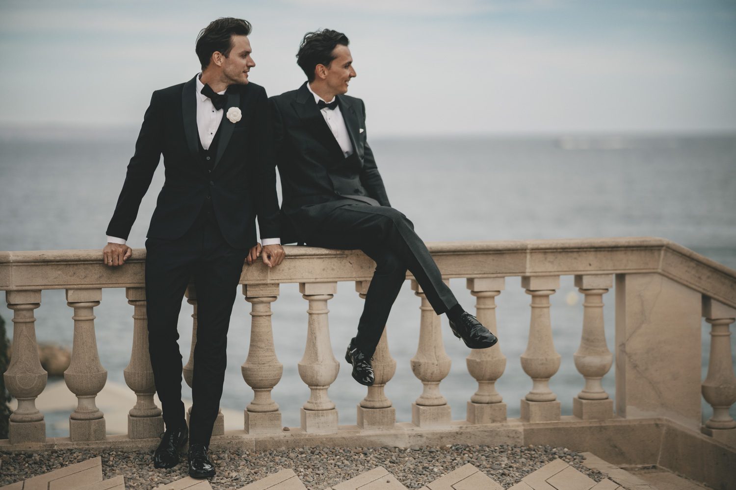 Two grooms sitting together above the sea.
