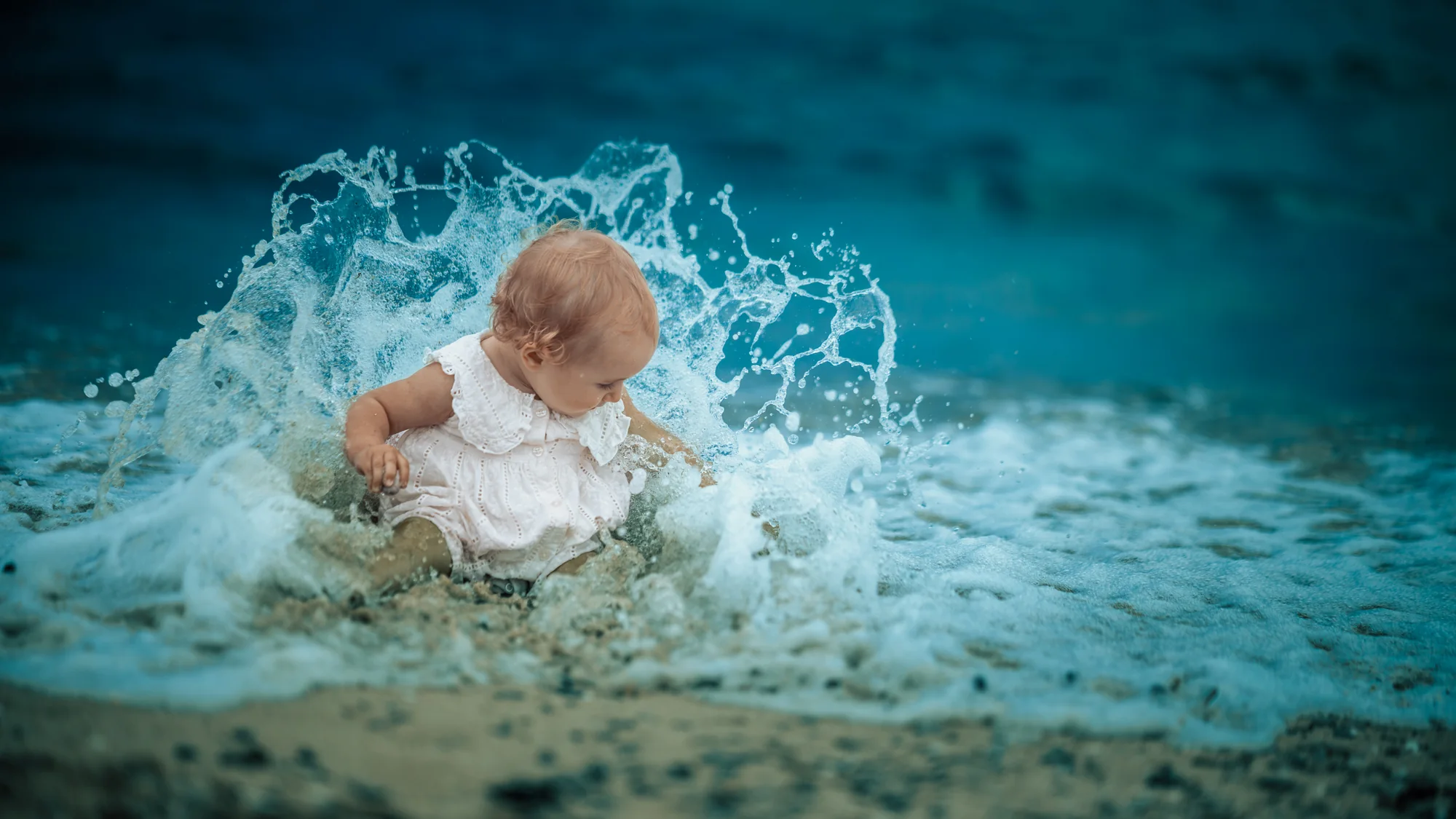 Small child sitting in shallow water as a wave breaks