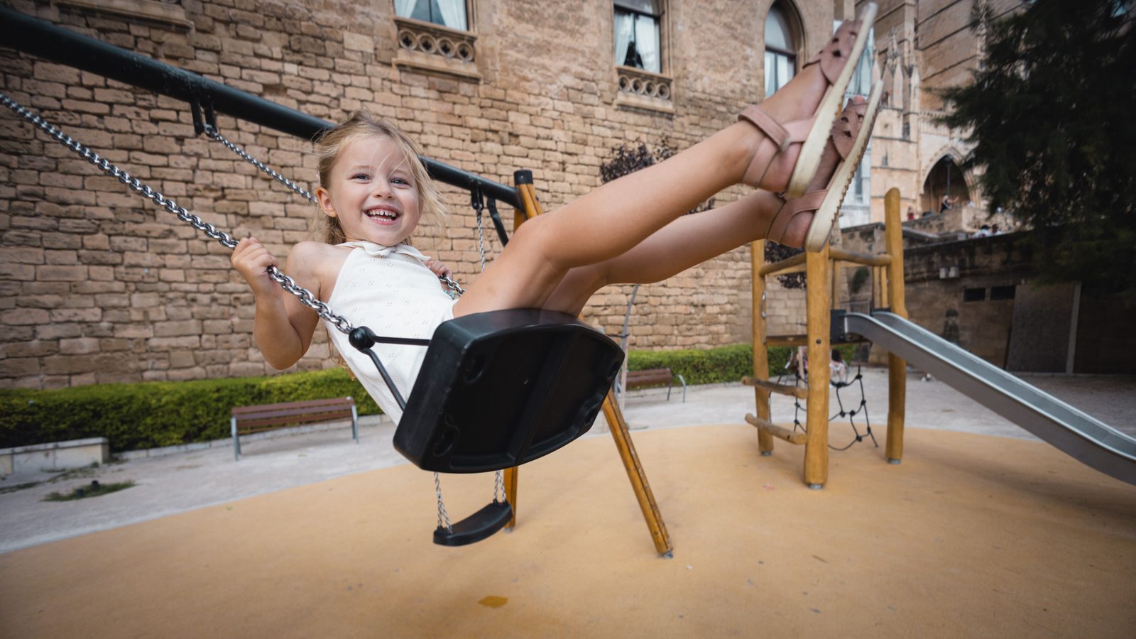 Child laughing while playing on a swing.