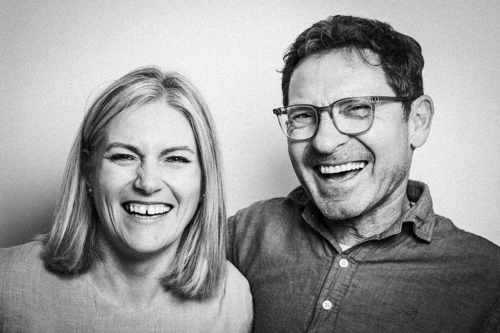 Two people laughing together in a simple portrait.