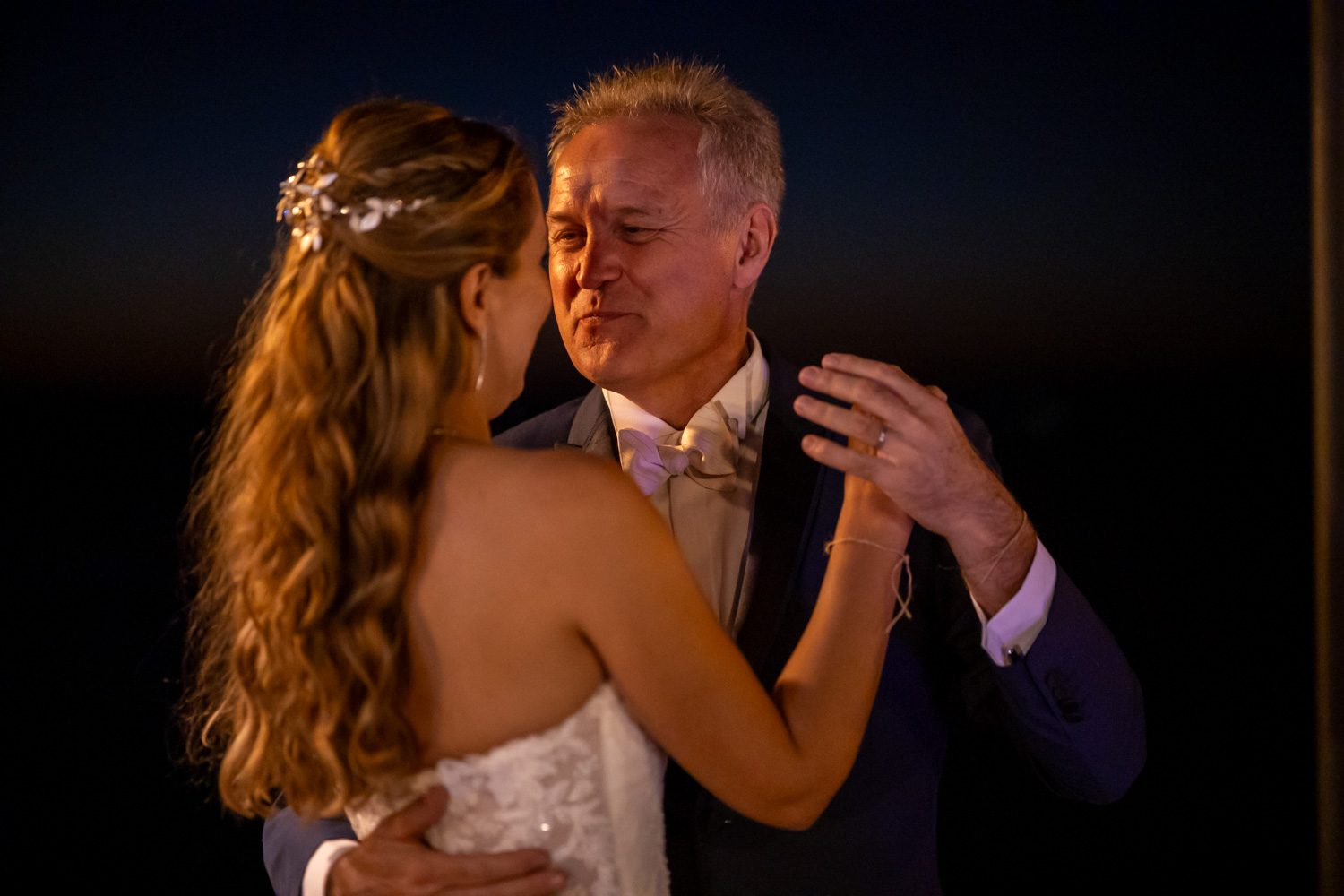 Bride dancing with an older family member at night.