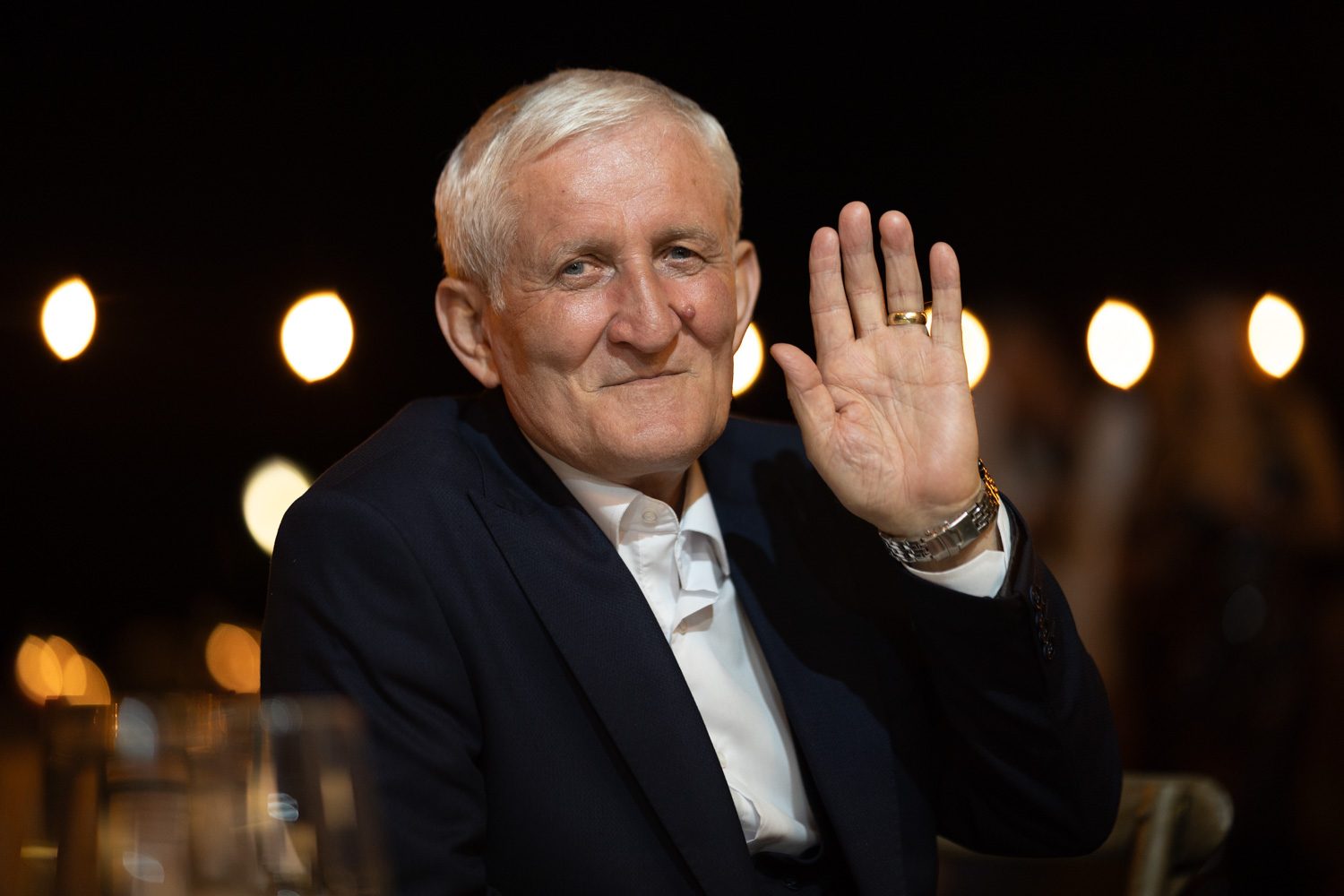 Older wedding guest waving during the evening celebration.