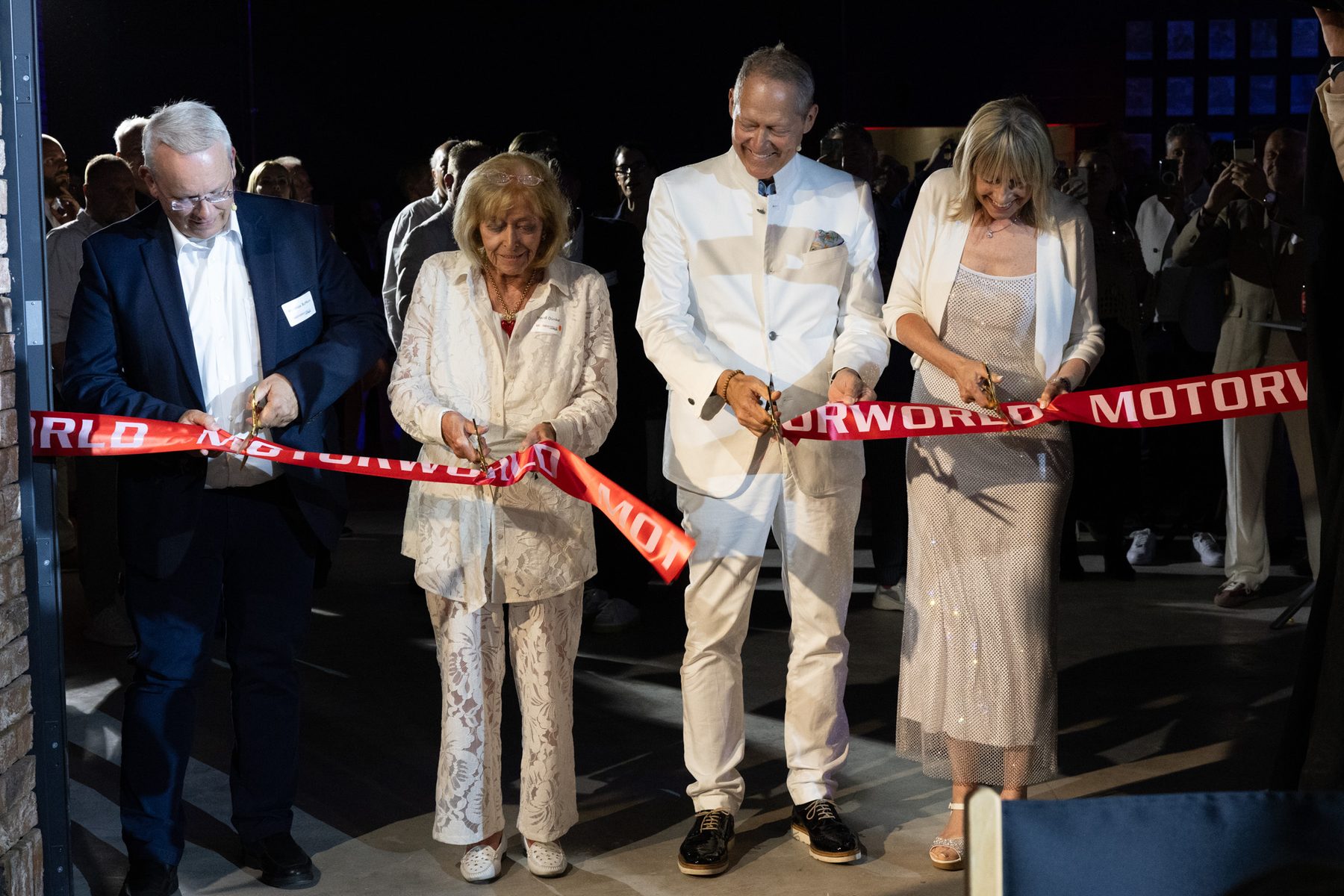 Guests cutting a ceremonial ribbon on stage.