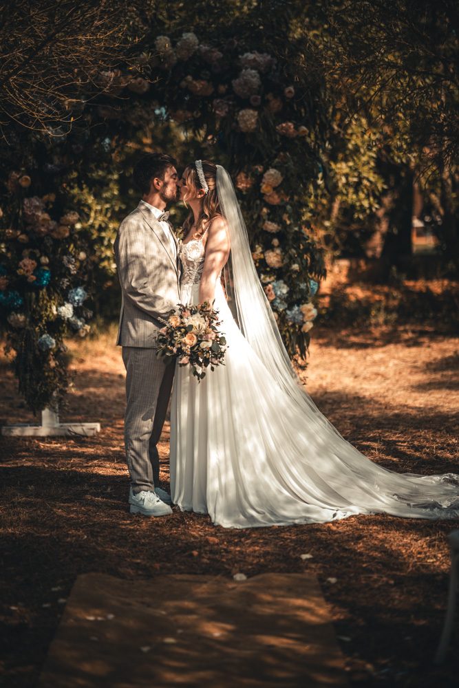 Newlyweds standing together in wooded evening light.