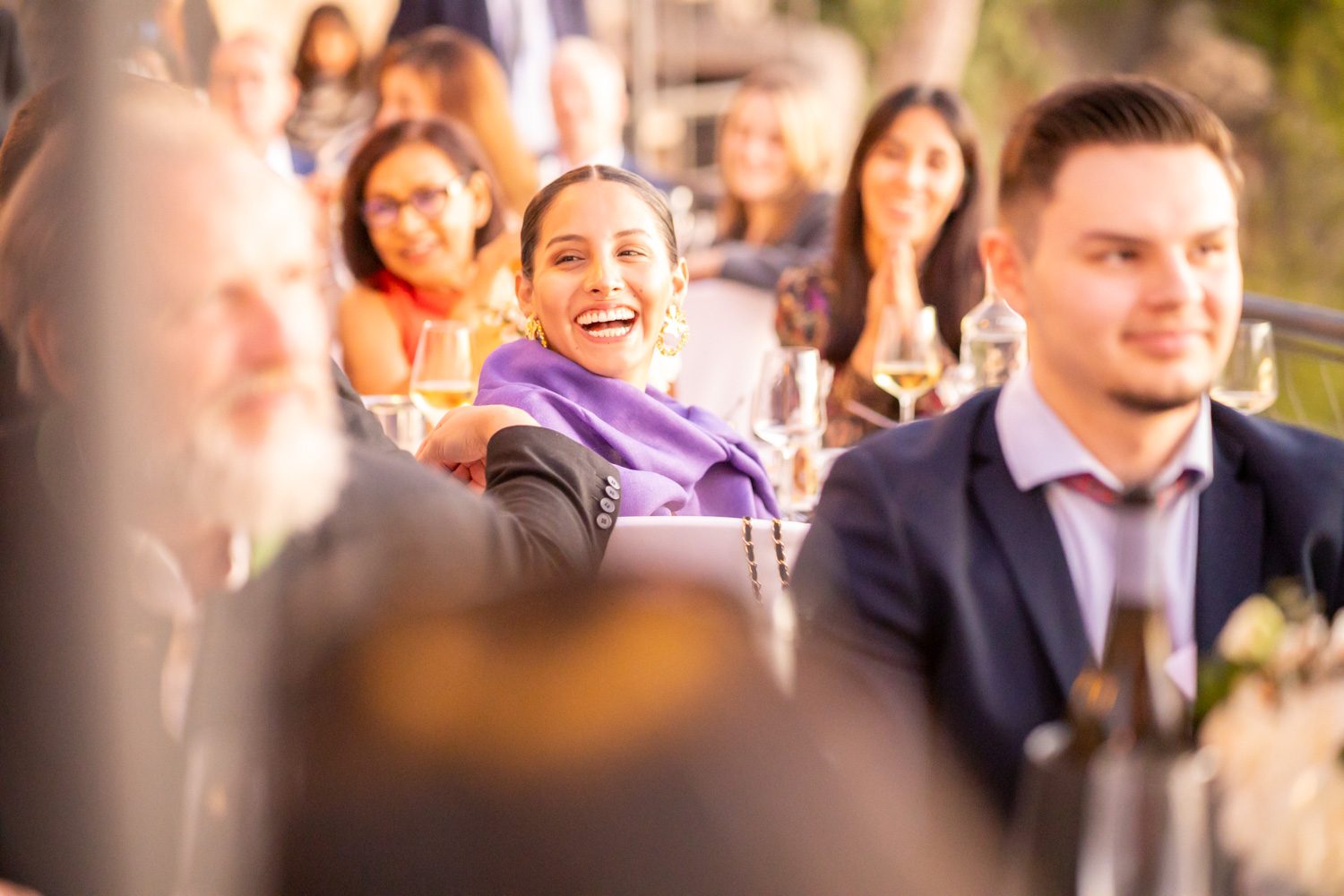 Wedding guests laughing during dinner speeches.