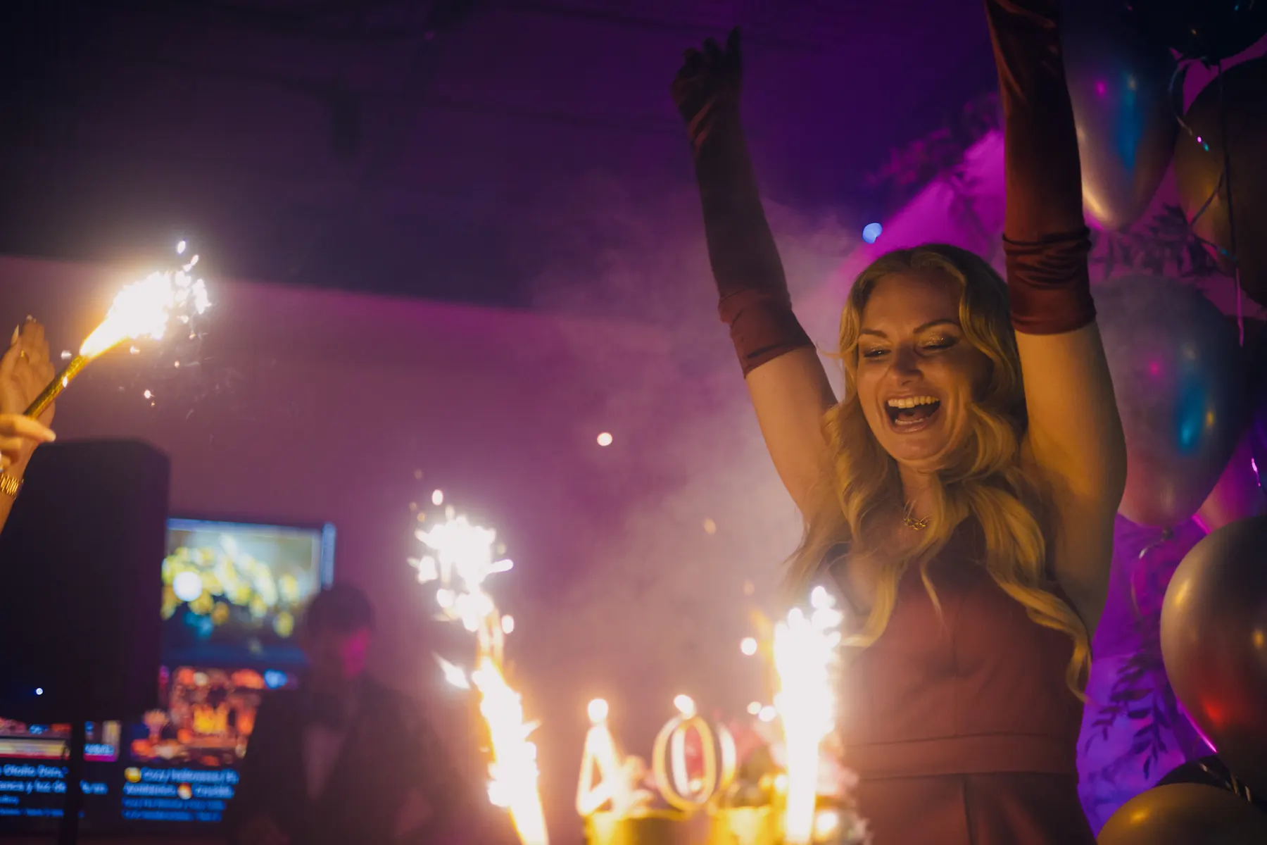 Woman celebrating at night with bright lights behind her