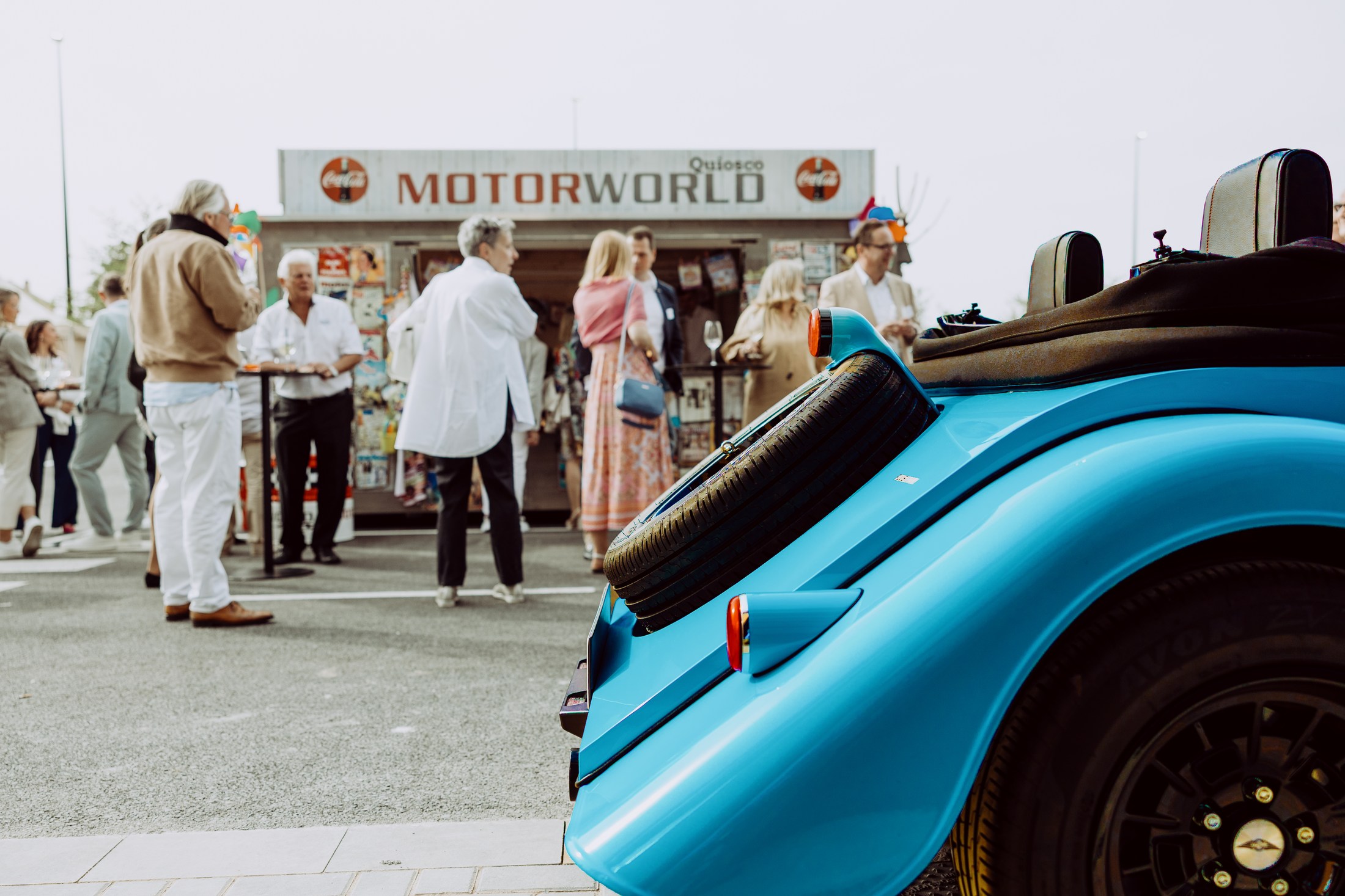 Guests gathering beside a blue sports car outside Motorworld Mallorca.