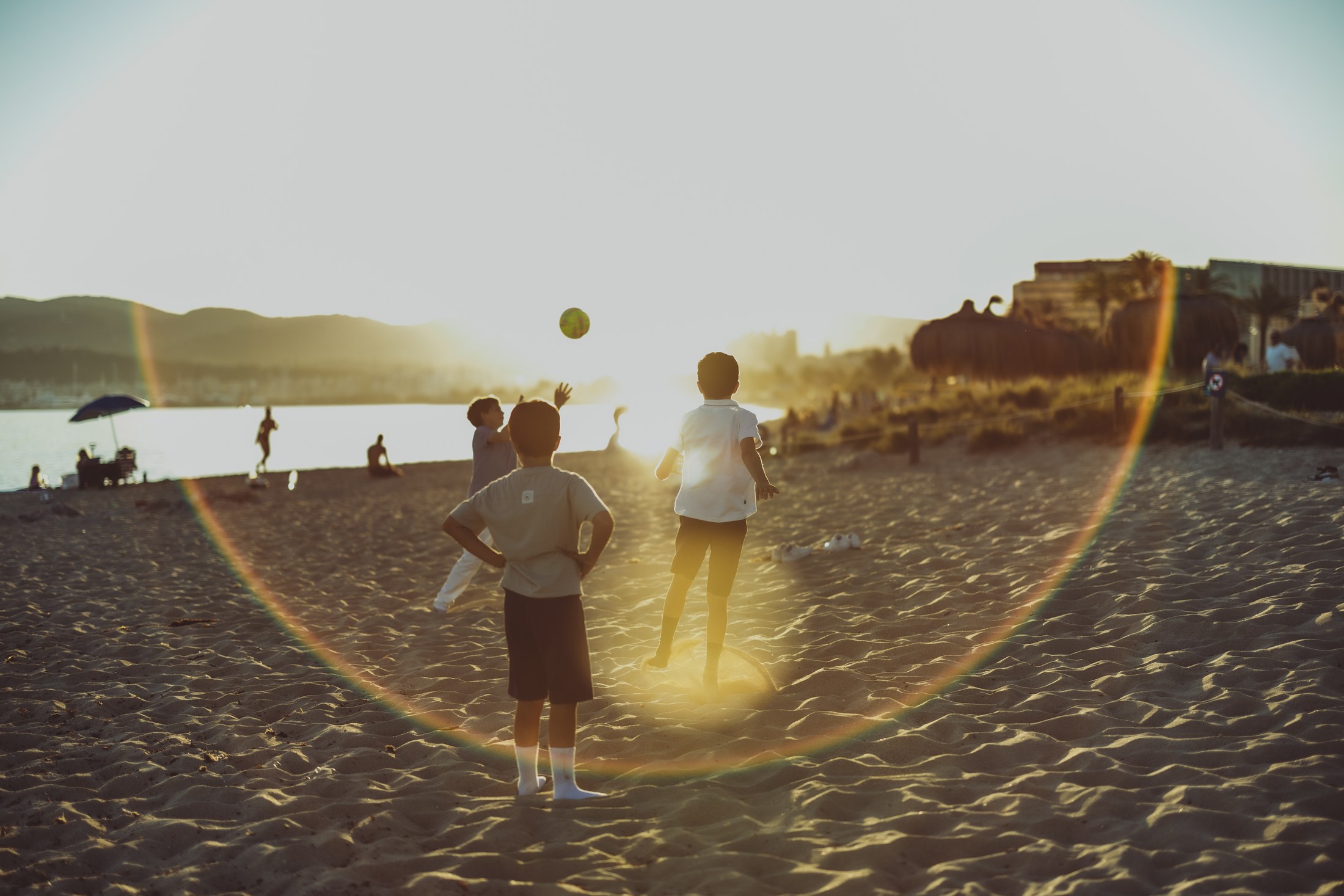 Children walking along a beach at sunset.
