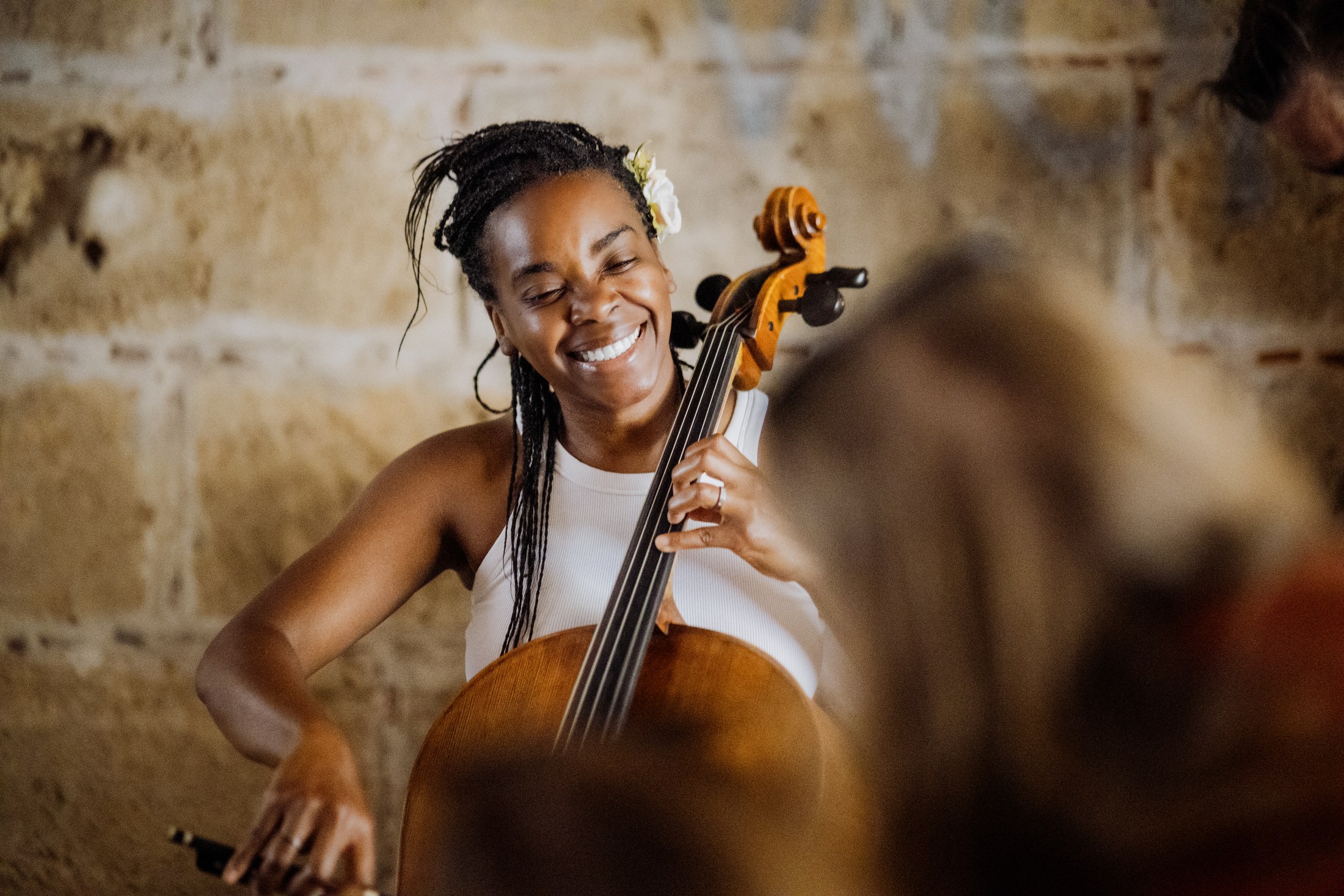 Cellist smiling while performing indoors.