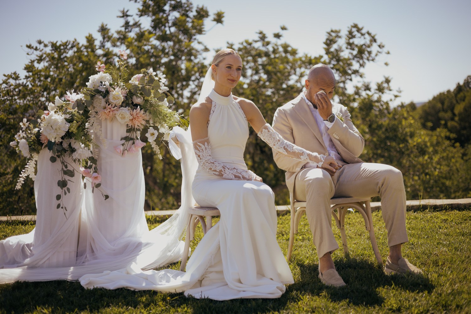 Bride and groom seated during an outdoor ceremony.