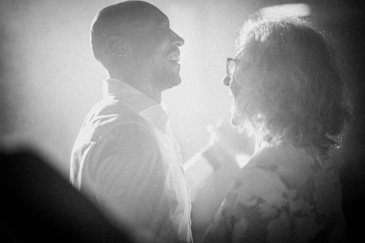 Bride and an older family member dancing in backlit black and white.
