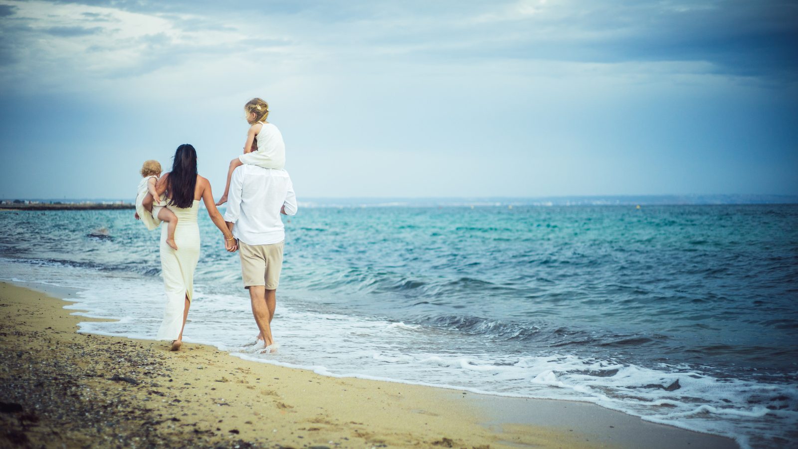 Family walking together along the sea.