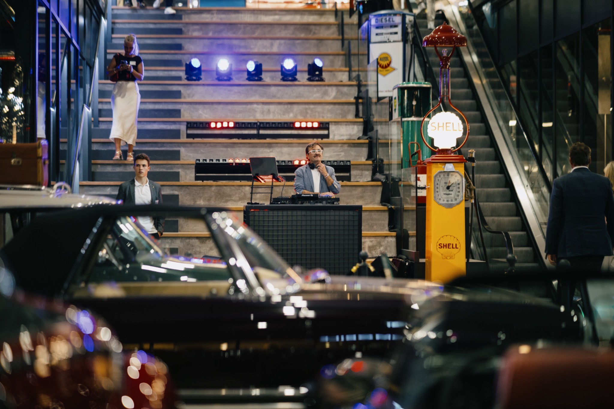 DJ and event setup inside Motorworld Mallorca with classic cars in the foreground