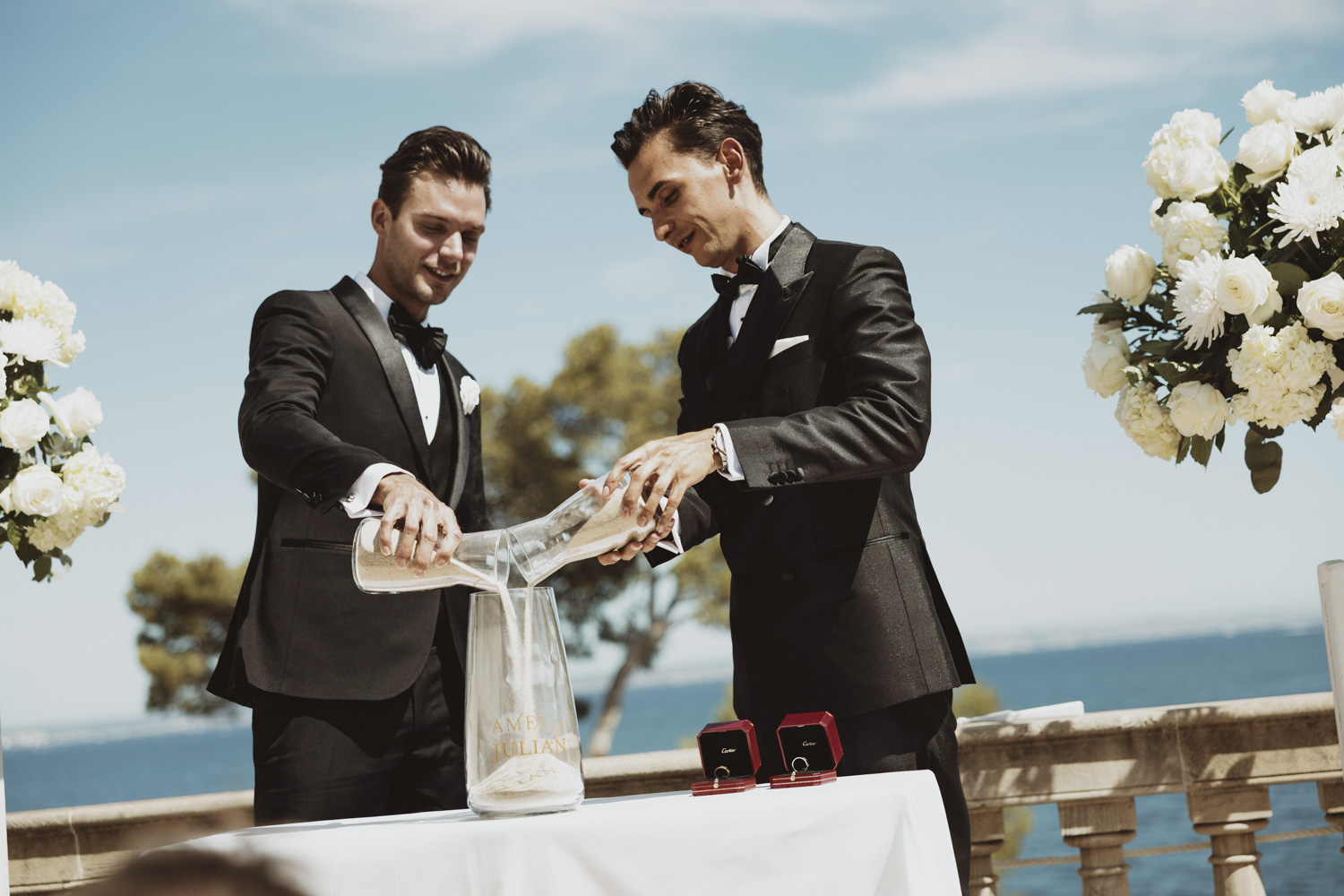 Two grooms taking part in a ceremony beside the sea.
